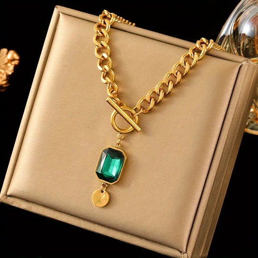 Collar con colgante de esmeralda y cadena gruesa dorada.